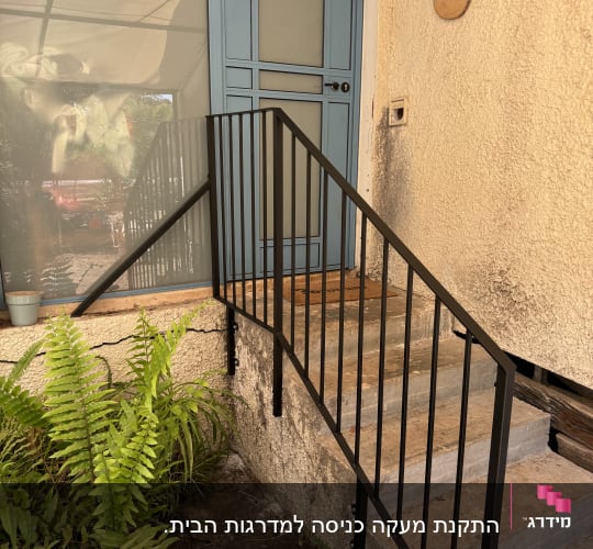 מעקה מתכת שחור ליד דלת כחולה